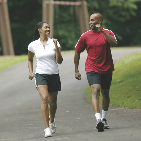 A man and woman power walking outside.