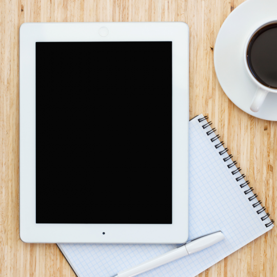 iPad on a table with notebook and coffee