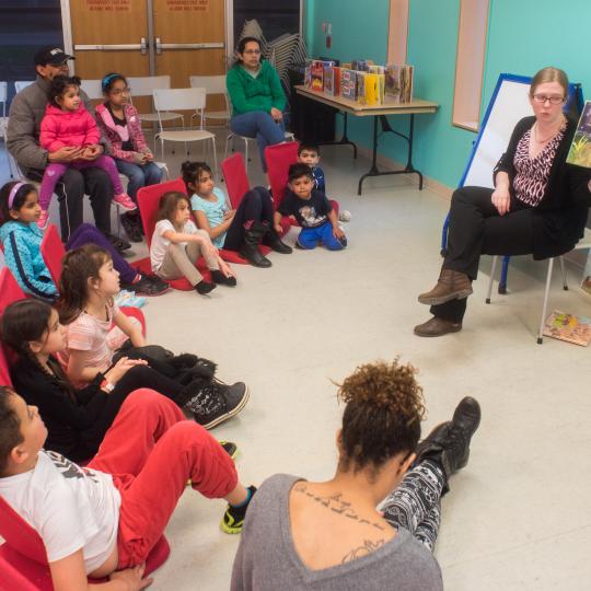 A Library staff member is speaking to a group of children in the Library.