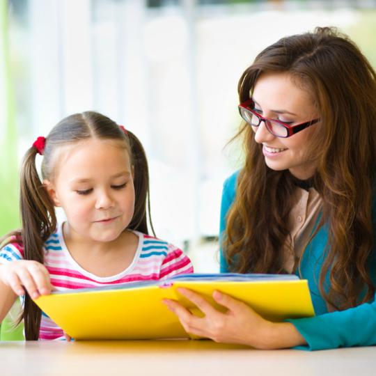 A woman and a child reading a book together. 